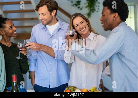 Groupe d'amis griller avec des verres à vin tout en accrochant à l'intérieur Banque D'Images