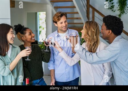 Group of friends toasting with wineglasses while hanging indoors Stock Photo