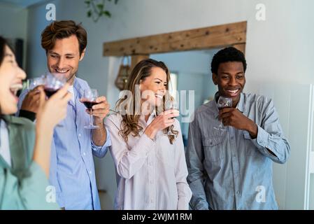 Groupe d'amis célébrant le toast avec des verres à vin dans la chambre domestique Banque D'Images