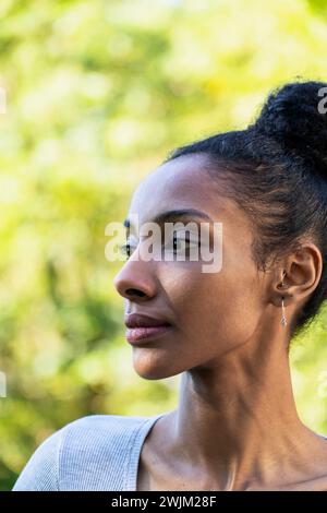 Vue de côté portrait de jeune femme adulte regardant sur le côté debout à l'extérieur Banque D'Images