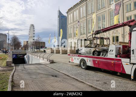 Leipzig, Allemagne. 16 février 2024. Une BMW Z3 brûlée est sur une dépanneuse après avoir été secourue du parking souterrain Augustusplatz. Le service des enquêtes criminelles enquête actuellement sur un incendie dans le parking souterrain situé sous Augustusplatz de Leipzig. Pendant la nuit, deux voitures ont été complètement détruites dans l'incendie et une autre voiture et une camionnette ont été endommagées. Le parking souterrain côté Opéra reste fermé jusqu'à ce qu'un ingénieur en structure l'ait inspecté. Crédit : Jan Woitas/dpa/Alamy Live News Banque D'Images