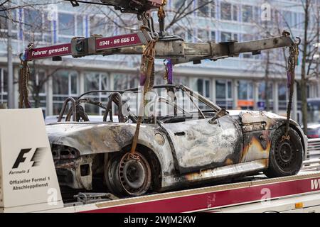 Leipzig, Allemagne. 16 février 2024. Une BMW Z3 brûlée est sur une dépanneuse après avoir été secourue du parking souterrain Augustusplatz. Le service des enquêtes criminelles enquête actuellement sur un incendie dans le parking souterrain situé sous Augustusplatz de Leipzig. Pendant la nuit, deux voitures ont été complètement détruites dans l'incendie et une autre voiture et une camionnette ont été endommagées. Le parking souterrain côté Opéra reste fermé jusqu'à ce qu'un ingénieur en structure l'ait inspecté. Crédit : Jan Woitas/dpa/Alamy Live News Banque D'Images