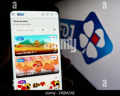 Personne tenant le téléphone portable avec la page web de la société française de loterie française des Jeux (FDJ) devant le logo. Concentrez-vous sur le centre de l'écran du téléphone. Banque D'Images