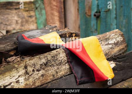 Le drapeau de l'Allemagne repose sur de vieilles planches dans une cour en Ukraine gros plan Banque D'Images