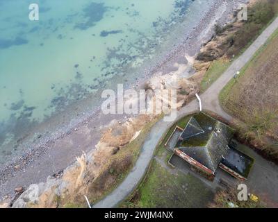 PRODUCTION - 14 février 2024, Schleswig-Holstein, Lübeck-Travemünde : vue sur les falaises et le centre de jeunes 'Haus Seeblick' de l'organisation de jeunes 'SJD - Die Falken', sur les falaises de Brodten sur la mer Baltique (tir par drone). Le centre de jeunesse 'Haus Seeblick', situé directement sur les falaises de Brodten, est fermé pour les enfants et le travail de la jeunesse après une autre démolition de bord. Seulement quatre bons mètres se trouvent entre un coin de la 'Haus Seeblick' et l'abîme. Fin janvier, un arbre est tombé le long du bord et a laissé un trou dans le sentier devant la maison. Photo : Marcus Brandt/dpa Banque D'Images