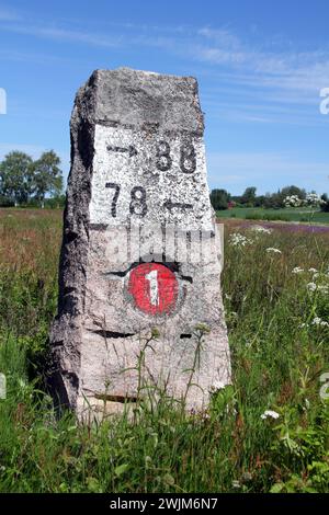 Ancien jalon en granit par la route 110 (anciennement numéro 1) à Kitula, Finlande avec paysage d'été. Banque D'Images