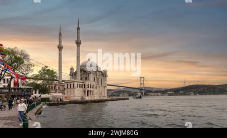 Istanbul, Turquie - 12 mai 2023 : une vue imprenable sur la mosquée d'Ortakoy située à côté du pont du Bosphore avec des minarets et des dômes scintillant dans les rayons au coucher du soleil dans Ortakoy neihborhood Banque D'Images