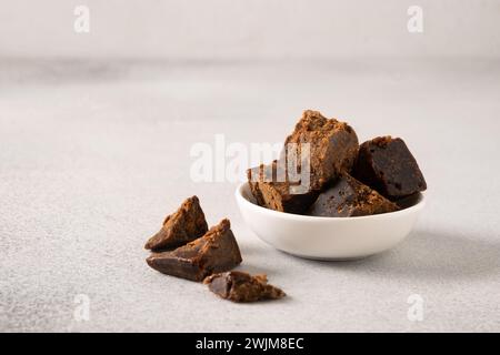 Édulcorant naturel Kithul jaggery et mélasse dans un bol blanc sur fond gris. Copier l'espace. Sucre alternatif et superaliment à faible indice glycémique. PA Banque D'Images