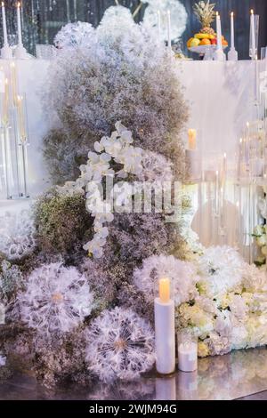 Un beau gâteau de mariage élégant orné de délicates fleurs blanches et de chandelles Banque D'Images