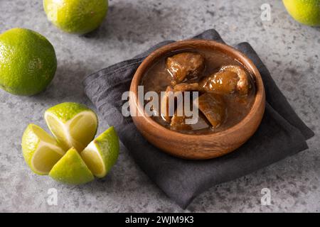 Traditionnel Sri Lanka Lime Pickle de citron vert, sel, piment, poivre dans un pot de conservation en verre sur fond gris. Gros plan. Cuisine de Ceylan. Banque D'Images