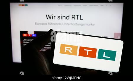 Personne tenant un smartphone avec le logo de la société de médias et de télévision RTL Group S.A. en face du site Web. Concentrez-vous sur l'affichage du téléphone. Banque D'Images