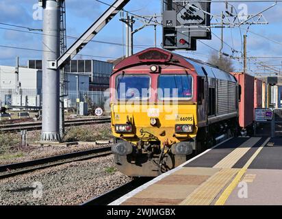 Une locomotive diesel de classe 66 dirige un train de marchandises de conteneurs vers le sud à travers la gare de Peterborough, Cambridgeshire, Angleterre, Royaume-Uni Banque D'Images