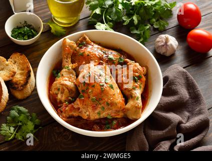 Ragoût de poulet géorgien avec tomates et herbes (chakhokhbili) dans un bol sur fond en bois. Viande de poulet cuite au four avec sauce tomate et légumes. E sain Banque D'Images