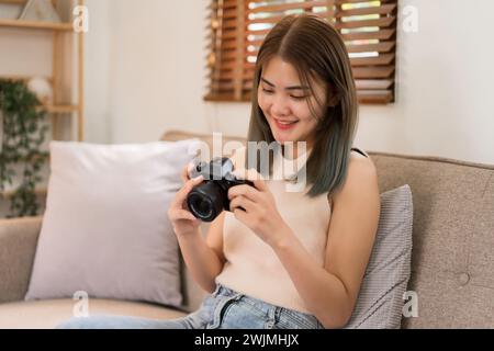 Concept de conception créative, créateur de mode assis sur le canapé pour vérifier la photo de nouveaux vêtements dans l'appareil photo. Banque D'Images