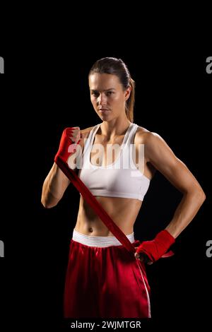 Jeune femme caucasienne pose en toute confiance dans l'équipement de boxe, avec un espace de copie Banque D'Images