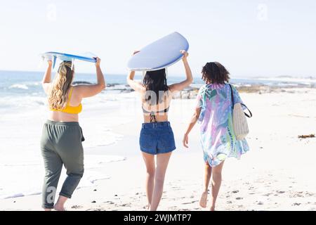 Une jeune femme caucasienne et deux jeunes femmes biraciales apprécient la plage Banque D'Images