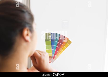 Une jeune femme biraciale examine des échantillons de couleur à la maison Banque D'Images