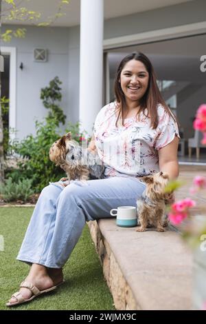 Jeune femme biraciale de taille plus profite d'un moment de détente à l'extérieur avec ses chiens Banque D'Images