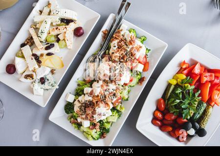 Table de buffet avec des plats blancs avec des tranches de fromage, divers légumes hors-d'œuvre froids dans le restaurant Banque D'Images
