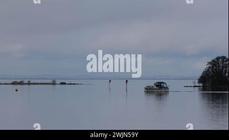 Lough Neagh, Kinnego, County Armagh, Irlande du Nord, Royaume-Uni. 16 février 2024. Météo britannique - une journée calme, principalement grise avec des sorts de nuages bas et de bruine. Un croiseur à moteur partant pour une courte course sur Kinnego Bay, Lough Neagh par une journée calme. Crédit : CAZIMB/Alamy Live News. Banque D'Images