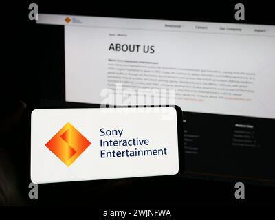 Personne tenant un smartphone avec le logo de la société américaine de jeux vidéo Sony Interactive Entertainment LLC en face du site Web. Concentrez-vous sur l'affichage du téléphone. Banque D'Images