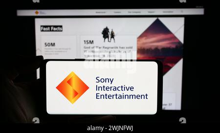 Personne tenant un téléphone portable avec le logo de la société américaine de jeux vidéo Sony Interactive Entertainment LLC en face de la page Web. Concentrez-vous sur l'affichage du téléphone. Banque D'Images