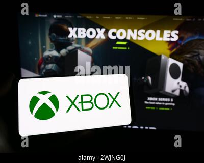 Personne tenant un smartphone avec le logo de la console de jeu vidéo Xbox (Microsoft) devant le site Web. Concentrez-vous sur l'affichage du téléphone. Banque D'Images