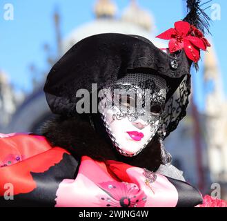 Venise, VE, Italie - 13 février 2024 : personne masquée avec rouge à lèvres et masque blanc pendant le carnaval vénitien Banque D'Images