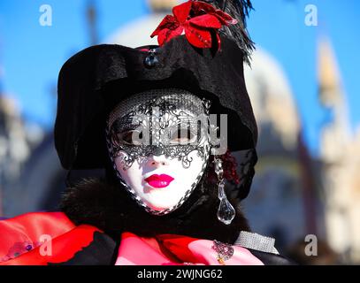 Venise, VE, Italie - 13 février 2024 : personne masquée avec rouge à lèvres et masque blanc pendant le carnaval vénitien Banque D'Images