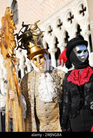 Venise, VE, Italie - 13 février 2024 : deux personnes avec des masques dorés et argentés symbolisant le soleil et la lune au Carnaval Banque D'Images
