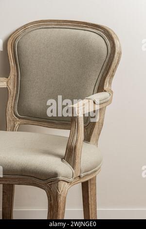 un fauteuil en bois clair non verni avec un siège rembourré gris dans une pièce aux murs blancs Banque D'Images