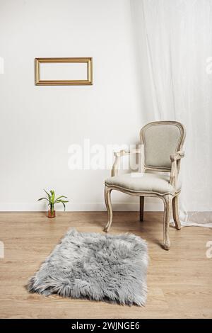 un fauteuil en bois clair non verni avec un siège rembourré gris, un tapis gris avec des rideaux blancs et un cadre en bois doré sur le mur Banque D'Images