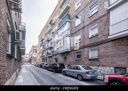 Façades de bâtiments résidentiels avec balcons sur une rue étroite et voitures garées dans une zone délimitée Banque D'Images