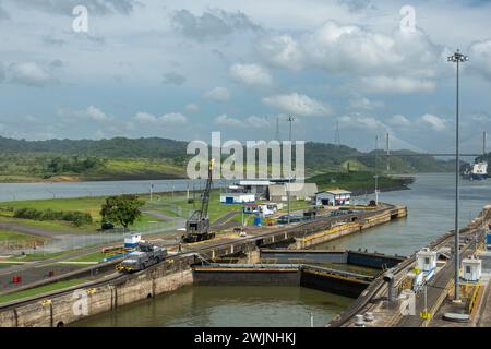 Canal de Panama, Panama - 24 juillet 2023 : les portes de sortie de Pedro Miguel s'enferment sous un nuage bleu. Côtes boisées vertes, porte-conteneurs à l'horizon Banque D'Images