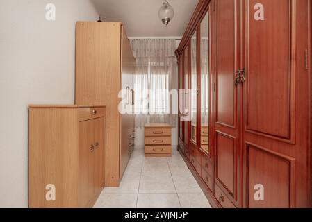 Petite chambre avec de grands placards remplissant tout avec du bois de couleur sapelly et des placards de couleur hêtre sur l'autre mur Banque D'Images