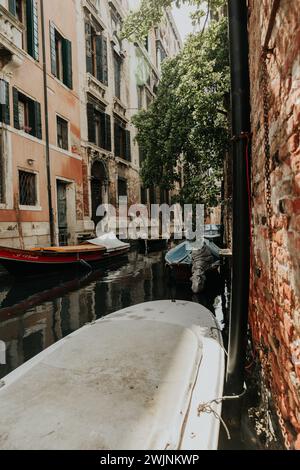 Un canal entre des bâtiments en briques avec des bateaux sur le rivage, entouré d'arbres, Venise, italie Banque D'Images