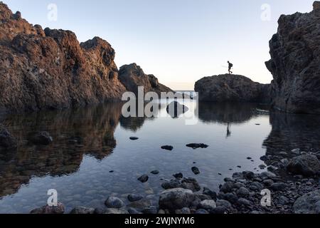 Un pêcheur se promène le long des rochers d'une piscine naturelle de Tenerife à l'aube. Photo de haute qualité Banque D'Images