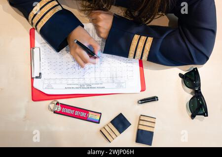 Pilote femme méconnaissable préparant la documentation de vol avec un porte-clés Remove Before Flight. Photo de haute qualité Banque D'Images