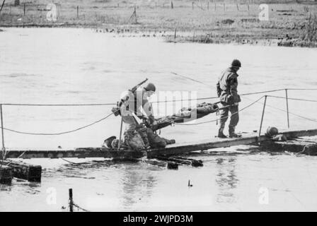 Blessé Yank transporté à travers Roer -- les porteurs de brancards portent un soldat américain blessé sur le corps d'un ami mort alors qu'ils négocient un pont temporaire sur la rivière Roer en Allemagne. Le soldat a été blessé et son copain tué lors de la traversée de la barrière allemande par les forces du yank, à la suite de quoi les Américains ont balayé vers le Rhin. 2 mars 1945. (Photo d'Associated Press photo). Banque D'Images