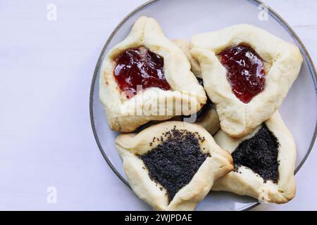 Variété de biscuits hamantaschen traditionnels remplis de pâte de mohn (pâte de graines de pavot) et de confiture de prunes pour le festival juif de Pourim. Vue de dessus de table. Banque D'Images