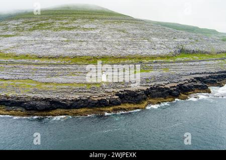 Black Head Lighthouse, situé dans le paysage rocheux rugueux de Burren, au milieu d'un paysage bizarre de montagnes calcaires escarpées et de côtes rocheuses, cou Banque D'Images