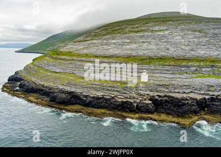 Black Head Lighthouse, situé dans le paysage rocheux rugueux de Burren, au milieu d'un paysage bizarre de montagnes calcaires escarpées et de côtes rocheuses, cou Banque D'Images