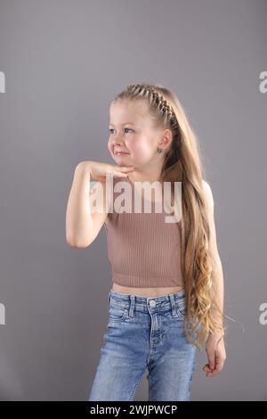 Petite fille avec les cheveux tressés sur fond gris Banque D'Images