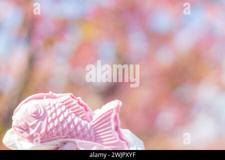 Magnifique Taiyaki rose (gâteau japonais en forme de poisson) avec fond de fleur de zakura Kawazu rose bokeh lors d'une journée ensoleillée du festival des cerisiers Kawazu Banque D'Images