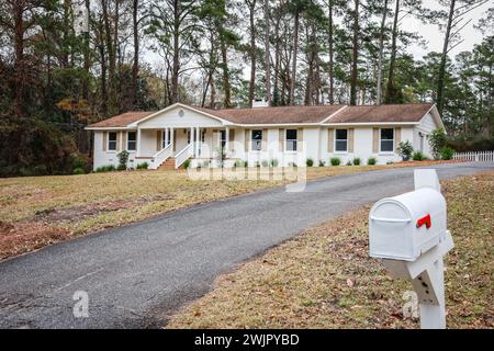 L'entrée extérieure avant d'une maison de style ranch en briques de parement blanc nouvellement peinte avec une grande cour qui a été récemment rénovée Banque D'Images