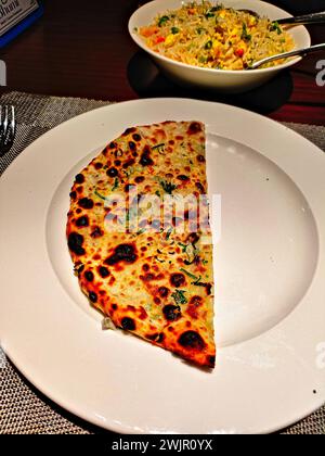 photo d'un naan de fromage à moitié tranché servi dans un plat blanc Banque D'Images