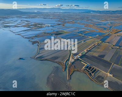 Vue aérienne de la baie d’Alfacs, des rizières et de la tour Sant Joan sur un coucher de soleil hivernal dans le delta de l’Èbre (Tarragone, Catalogne, Espagne) Banque D'Images