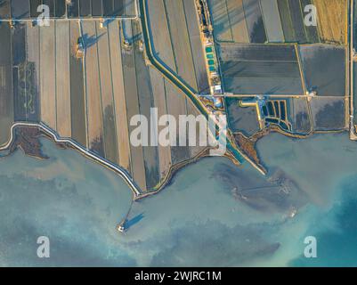 Vue aérienne de la baie d’Alfacs, des rizières et de la tour Sant Joan sur un coucher de soleil hivernal dans le delta de l’Èbre (Tarragone, Catalogne, Espagne) Banque D'Images