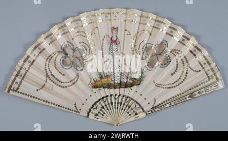 Gamme pliée, décor face : Domino en tulle en forme de trèfle à 4 feuilles, au centre, une jeune femme en robe blanche pailletée avec bustier argenté et rose, tenant une guirlande de rose, encadrant et décor en paillettes dorées autour des ouvertures de Domino (paillettes GAL1981.95.76 feuille de face: crème satin, peinture, visage peint., paillettes argent et or Banque D'Images