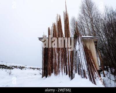 Longs poteaux en bois empilés avec de la neige sur eux. Matériau de construction dans la scène d'hiver Banque D'Images